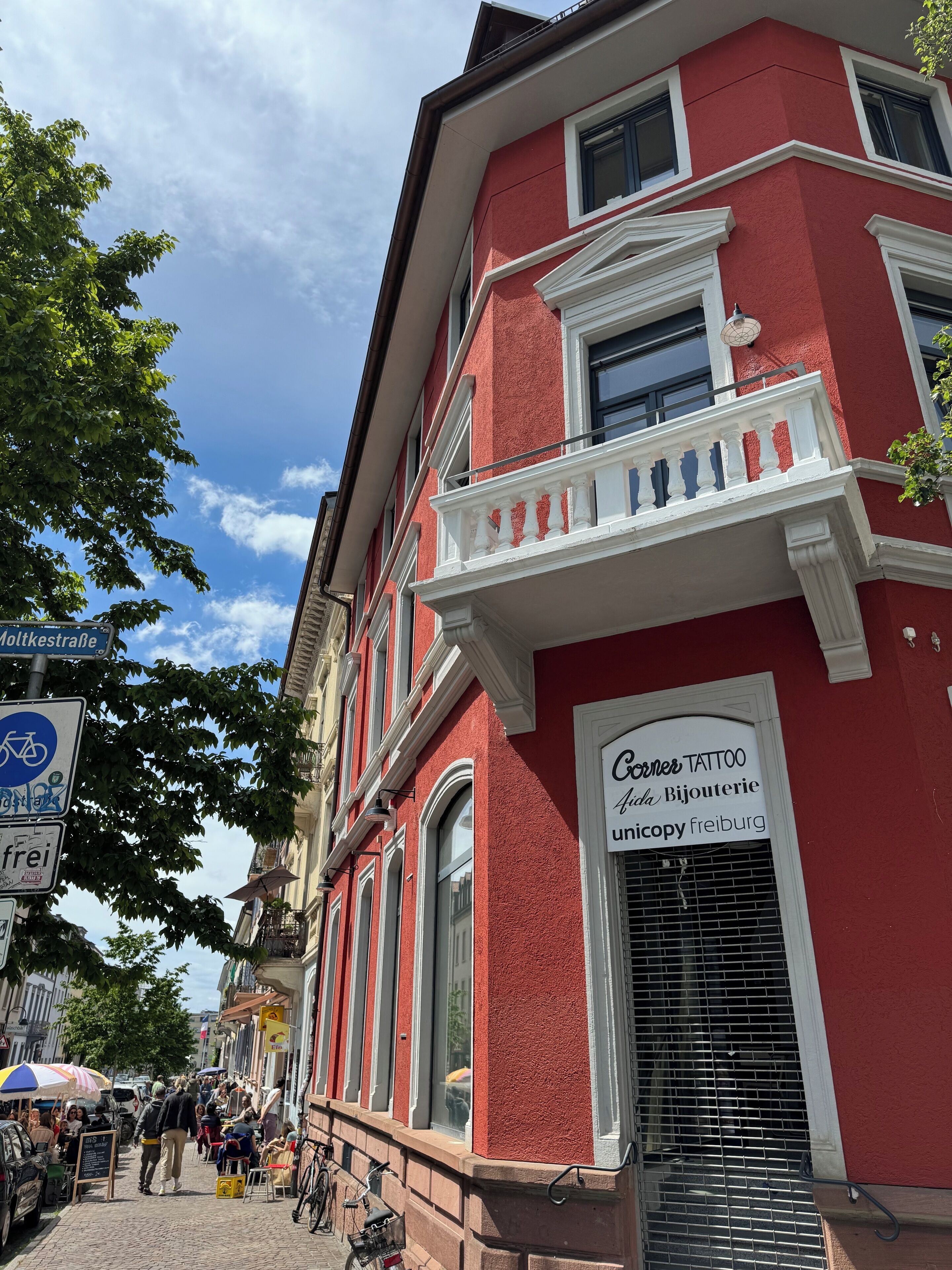 Um edifício vermelho com uma placa indicando Corner Tattoo.