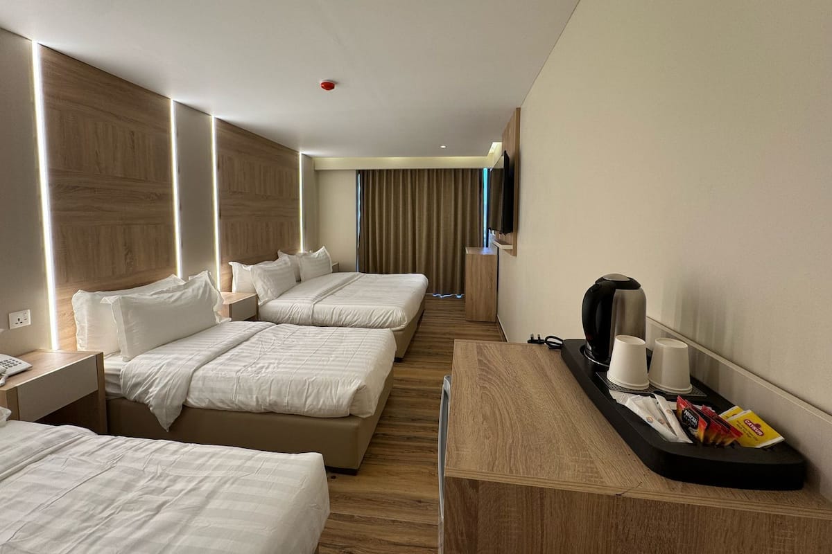 Une chambre d’hôtel avec deux lits, un bureau avec une machine à café et une télévision.