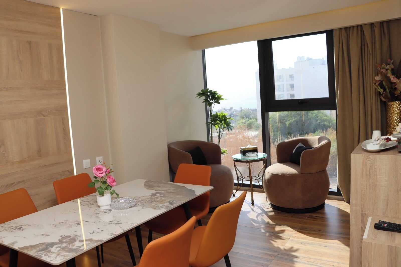 Un salon moderne avec un coin repas, de grandes fenêtres et une vue sur la ville.