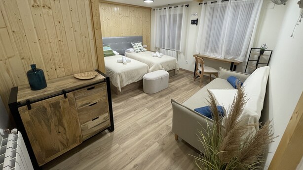 Habitación de hotel con dos camas, un sofá, una mesita y un radiador.