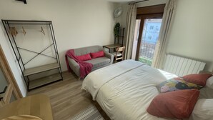 Un dormitorio con cama, sofá, escritorio y armario.