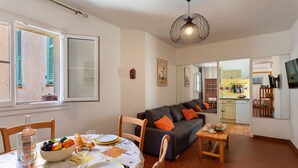 A dining area with a table set for two, a sofa, and a kitchen in the background. - VUE ROSSETTI AP4465 by Riviera Holiday Homes (Niza)