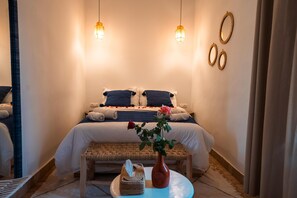 A hotel room with a bed, bedside tables, a bench, and a vase with flowers. - Le soleil de Bahia (Marrakech)