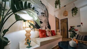 Una sala de estar con sofá, un adorno de pared, una lámpara y una planta en maceta.