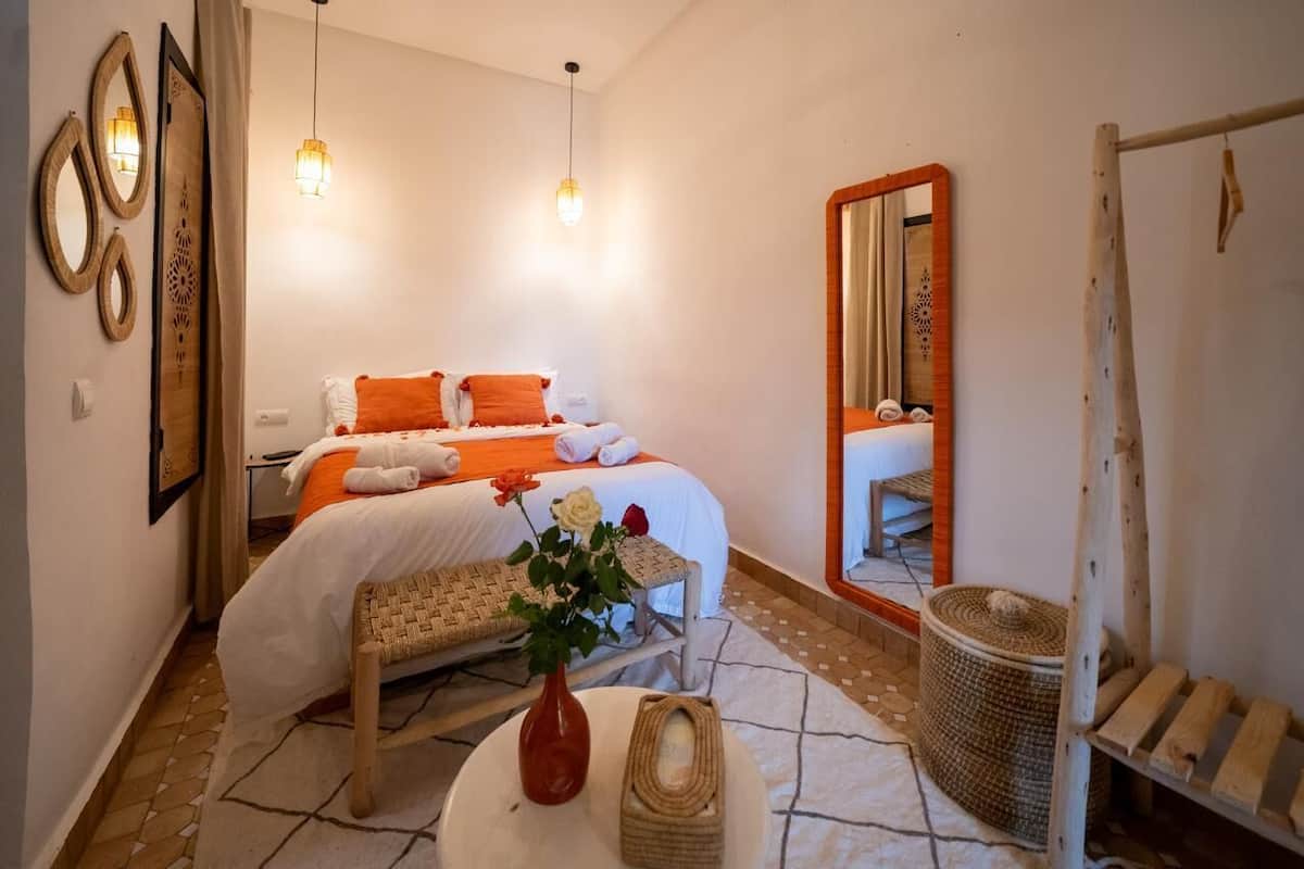 A bedroom with a bed, bedside table, and a mirror.