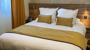 Een hotelkamer met een groot bed, een houten hoofdeinde en een structuurwand.