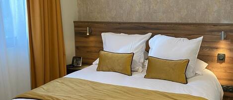 A hotel room with a large bed, a wooden headboard, and a textured wall.