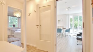 A modern interior with a white door leading to a dining area with blue chairs and a table. - Vacation home Bergstraße 62 Apartment 5 Tide am Park (Timmendorfer Strand)