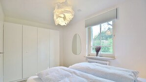 A bedroom with a bed, a window, a radiator, and a wardrobe. - Vacation home Bergstraße 62 Apartment 5 Tide am Park (Timmendorfer Strand)