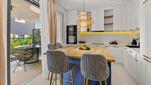 Een moderne keuken met een houten kookeiland, witte keukenkastjes en een hanglamp.