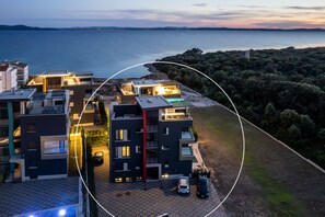 Um complexo residencial moderno com vários edifícios, piscina e vista para o mar.