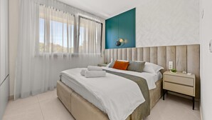 A modern bedroom with a large bed, a nightstand, and a view of the outdoors through sheer curtains. - The Adriatic - Luxury Waterfront Apartment (Zadar)
