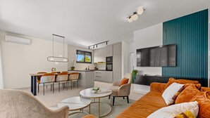 A modern living room with a sofa, coffee table, and dining area. - The Adriatic - Luxury Waterfront Apartment (Zadar)