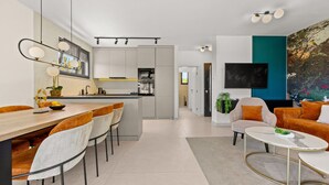 A modern living room with a dining area, a kitchen, and a TV mounted on the wall. - The Adriatic - Luxury Waterfront Apartment (Zadar)