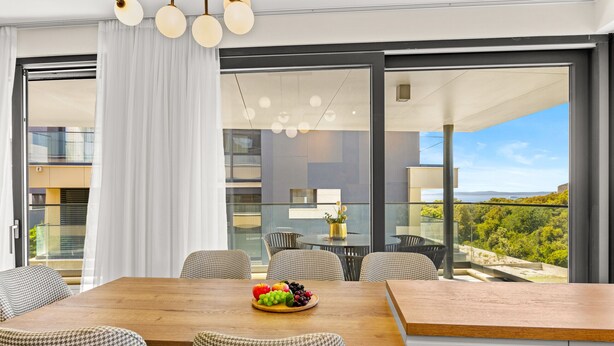 A modern dining area with a wooden table, checkered chairs, and a view of the outdoors. - The Riviera Three - Luxury Waterfront Apartment (Zadar)