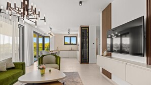 A modern living room with a green sofa, a coffee table, and a large TV. - The Riviera Three - Luxury Waterfront Apartment (Zadar)