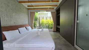 Une chambre moderne avec un grand lit, des poutres en bois au plafond, un mur en béton et une vue sur la verdure.