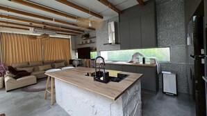 A modern kitchen with a central island, built-in appliances, and a stone-textured backsplash. - The Ten Poolvilla Huahin (Hin Lek Fai)