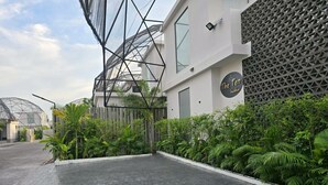 A modern building with a geometric facade, a sign reading "The Ten", and a paved walkway with lush greenery. - The Ten Poolvilla Huahin (Hin Lek Fai)