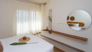 Een hotelkamer met een bed, een nachtkastje met dienblad, een spiegel en een wandplank.