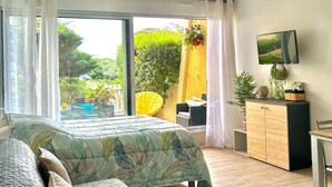 Un dormitorio con cama, ventilador de techo, televisor y vistas al exterior.