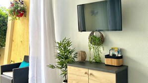 Una sala de estar moderna con un televisor de pantalla plana montado en la pared, un mueble de madera con una cesta y una planta en maceta.