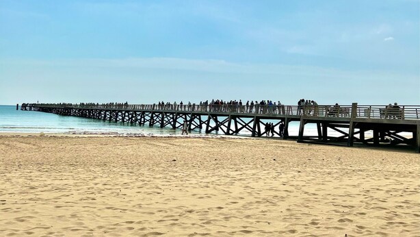 Una playa con un muelle que se adentra en el agua.