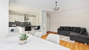 Un espacio habitable moderno con comedor, cocina y zona de estar con sofá.