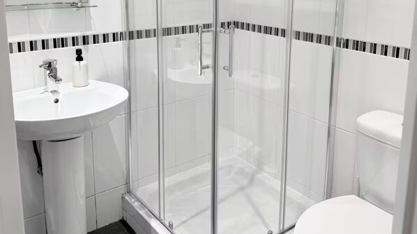 A modern bathroom with a glass-enclosed shower, a white sink, and a toilet. - South Dublin Oasis (Dublin)