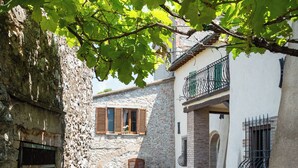 A narrow cobblestone alley with stone buildings, a wooden door, and a small table with chairs.