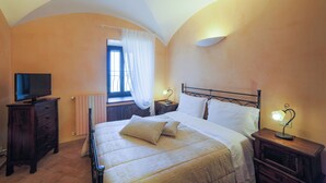 A bedroom with a bed, bedside tables, a TV, and a window with curtains.