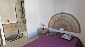 Relax in a serene bedroom with a large bed, glass shower, and modern amenities.
