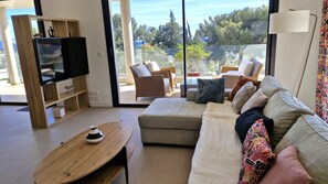 Relax in style with a large TV, plush sofa, and comfortable seating area overlooking a serene outdoor space.