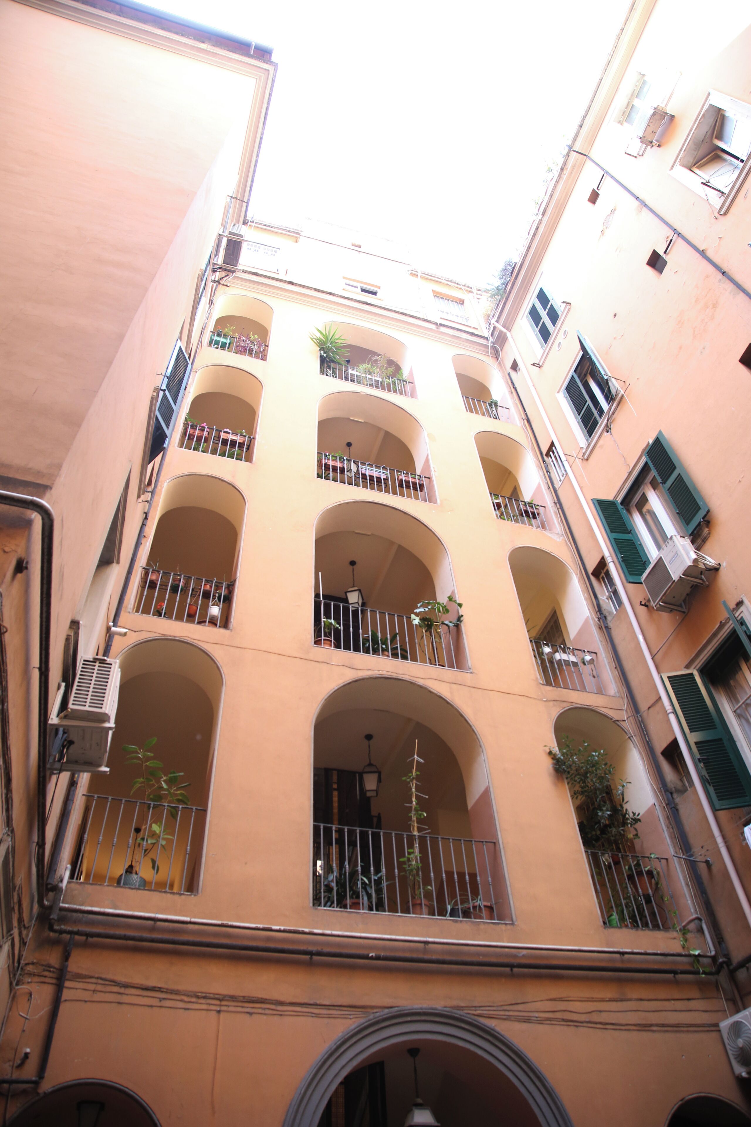 Un immeuble à plusieurs étages doté de balcons, de climatiseurs et de fenêtres en arc de cercle.