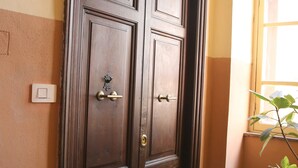 A wooden double door with a doorknob and a keyhole, a doormat with "HOME" written on it, and a potted plant beside a window.