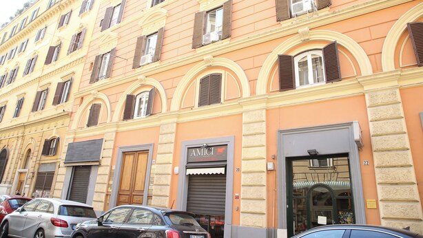 A multi-story building with a row of parked cars in front.