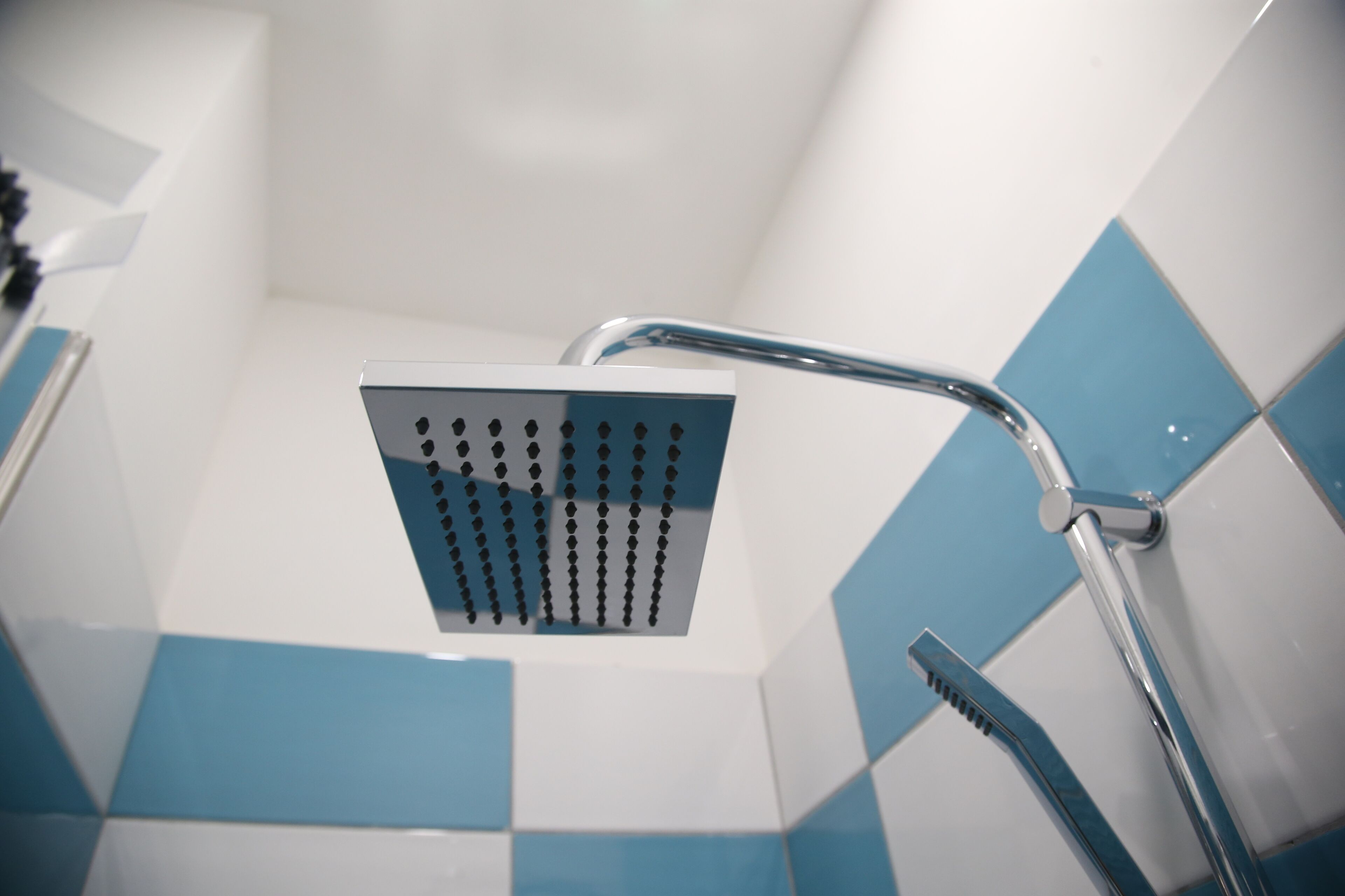 Douchekop met vierkant ontwerp en chromen handgreep.