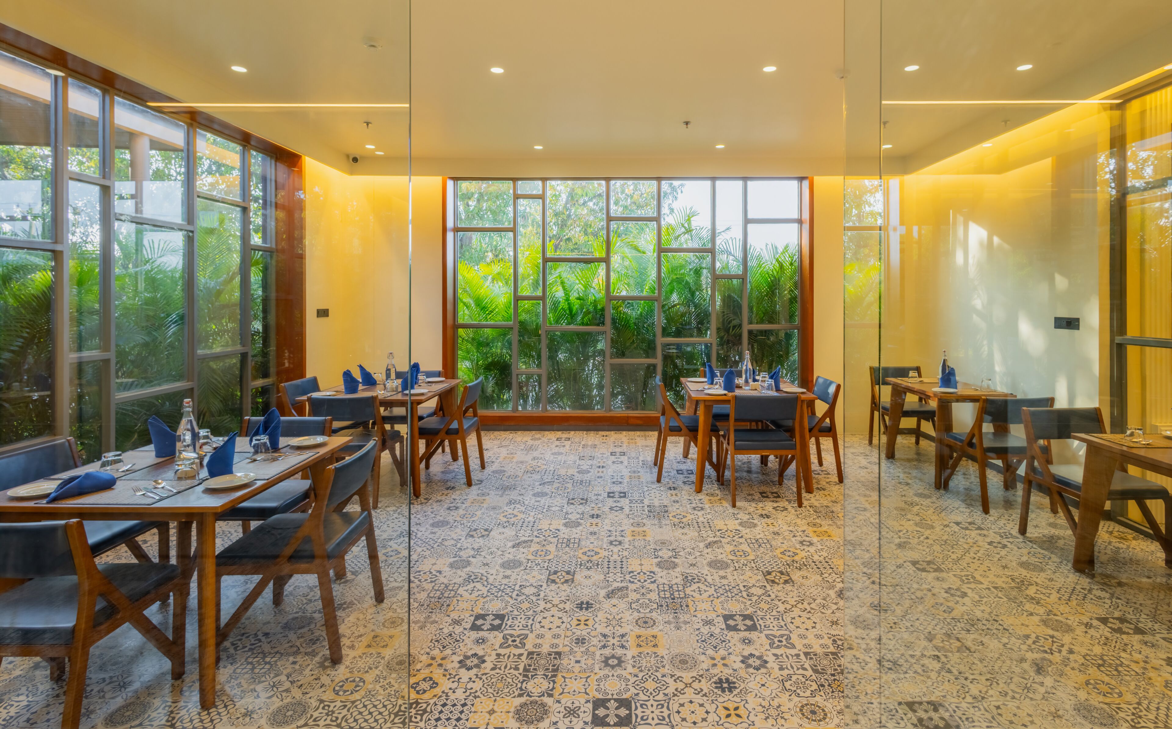 A dining area with tables and chairs, large windows, and a patterned floor.
