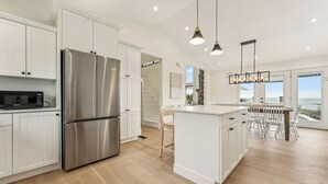 A modern kitchen with white cabinetry, stainless steel appliances, and a large island with seating.