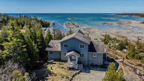 A two-story house with a front porch and a view of the ocean.