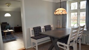 Un espace repas comprenant une table et des chaises, un luminaire suspendu et une vue par la fenêtre.