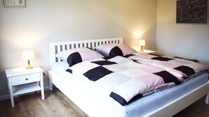 Un lit bien fait, recouvert d’une couverture matelassée, avec deux lampes de chevet.