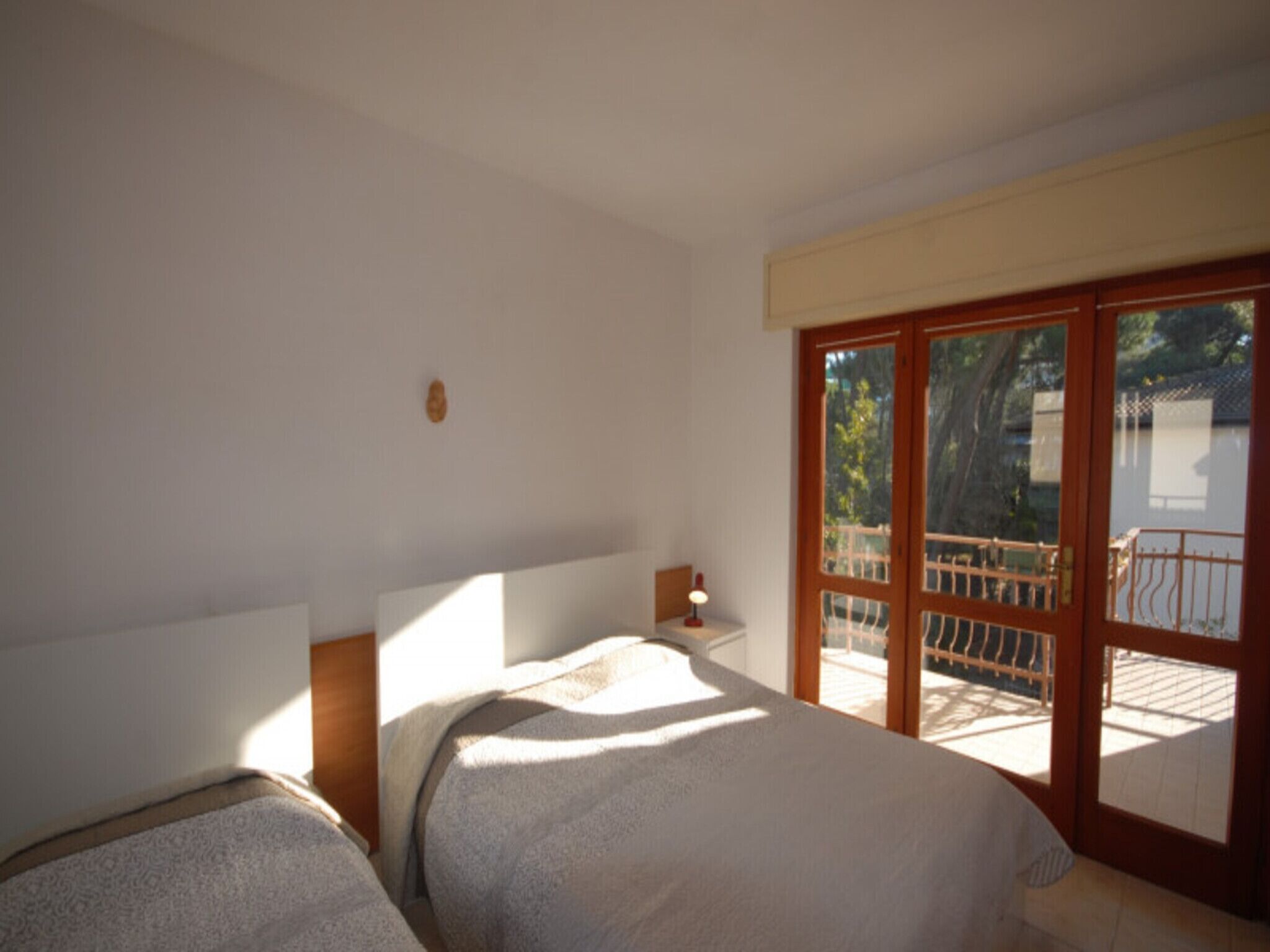 A bedroom with two beds, a nightstand, and a view of the outside balcony.