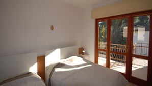 Une chambre avec deux lits, une table de chevet et une vue sur le balcon extérieur.