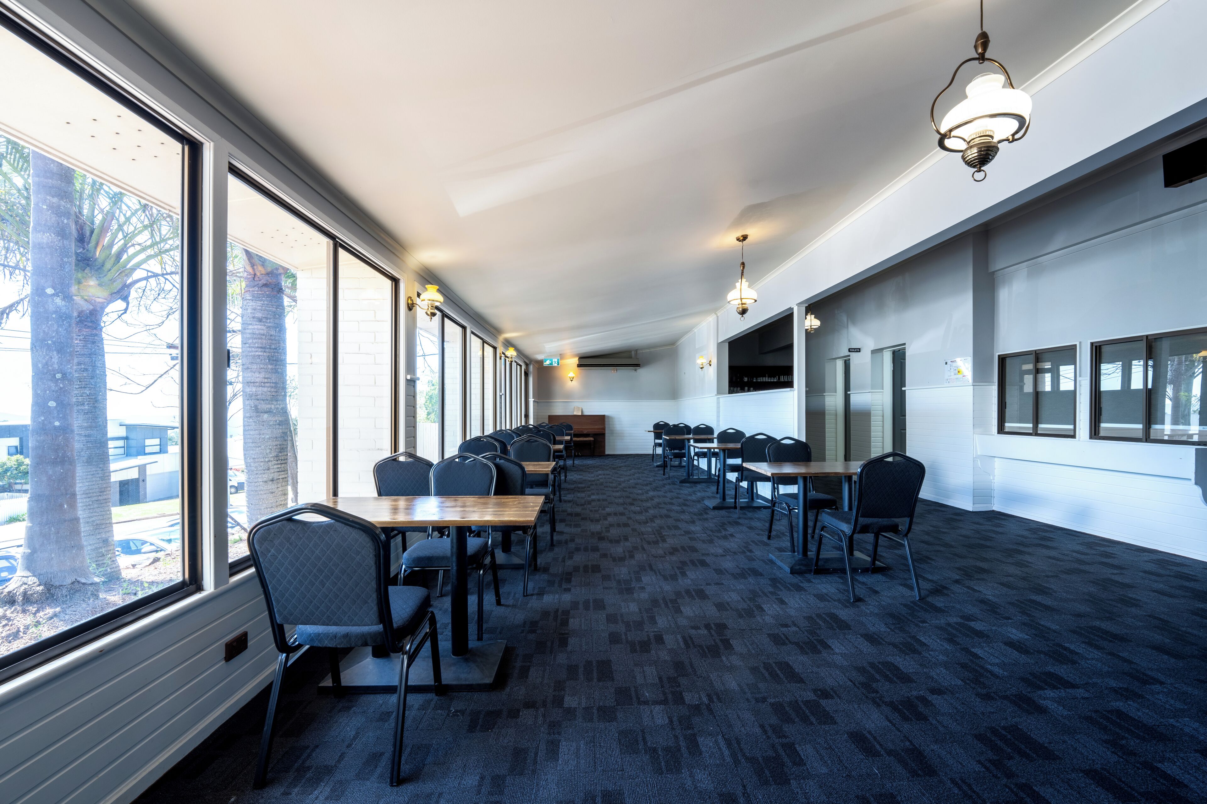 Une salle de conférence équipée de tables et de chaises, dotée de grandes fenêtres et recouverte d’un tapis.