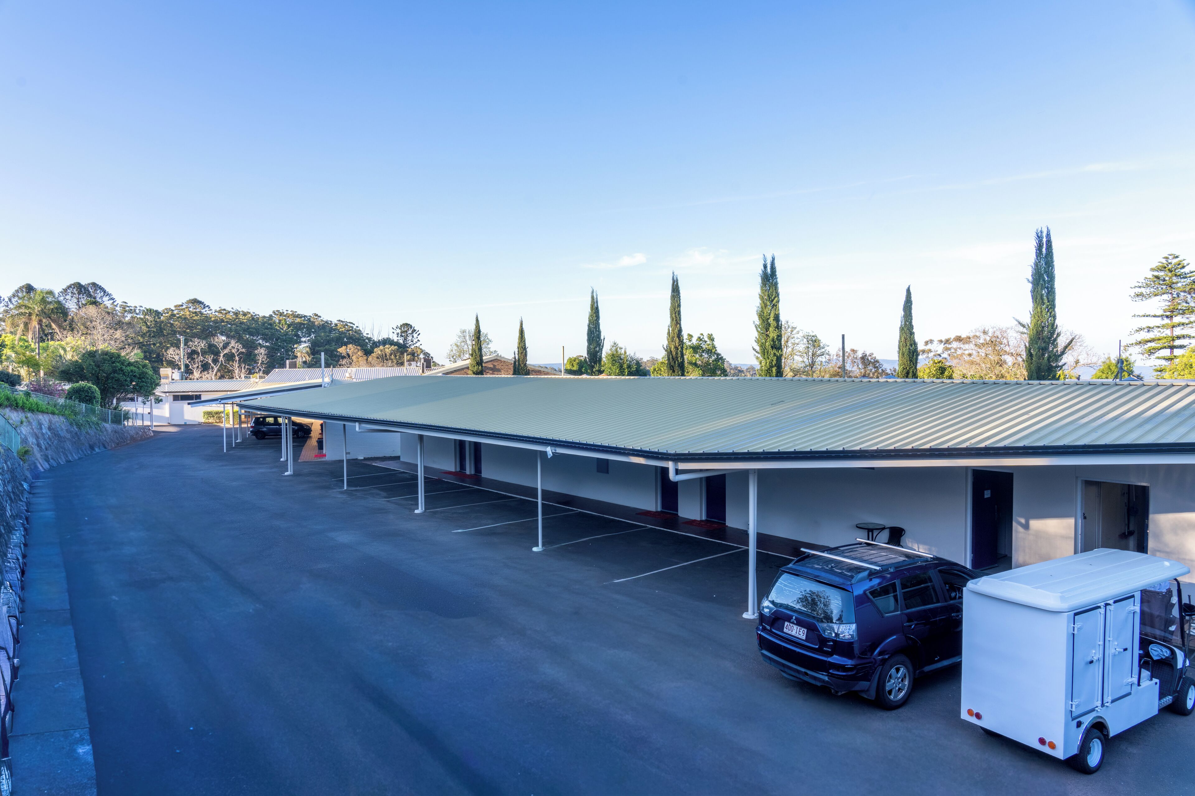 A parking area with a covered building, a truck, and a trailer.
