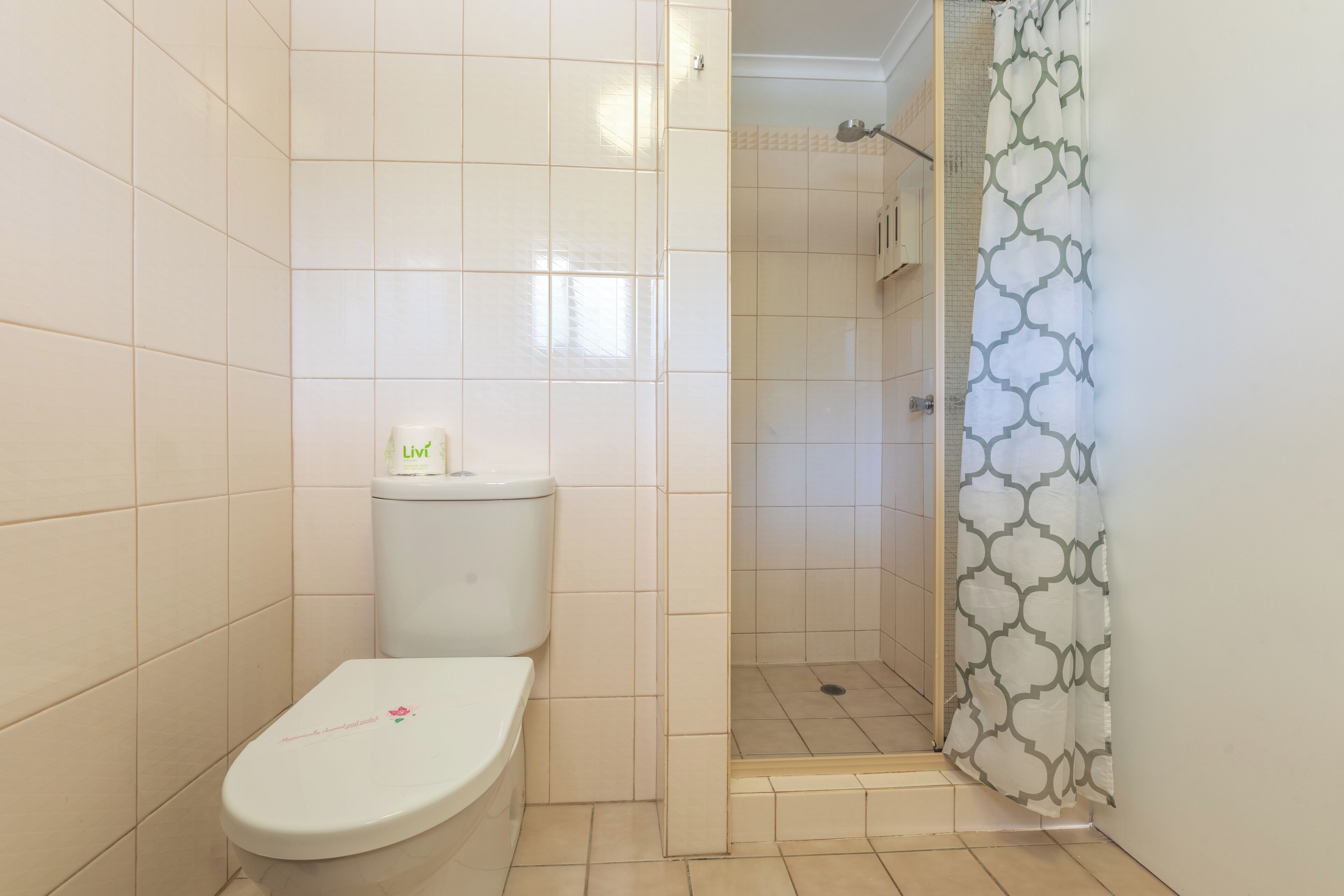 A bathroom with a toilet, a shower area, and a tiled floor.