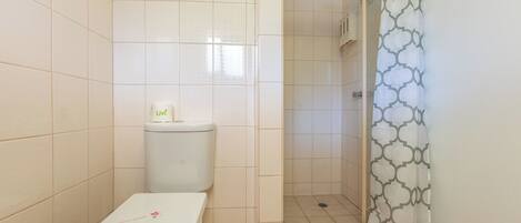 A bathroom with a toilet, a shower area, and a tiled floor.