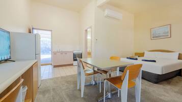 Une chambre d’hôtel moderne comprenant un coin repas, un lit et une kitchenette.
