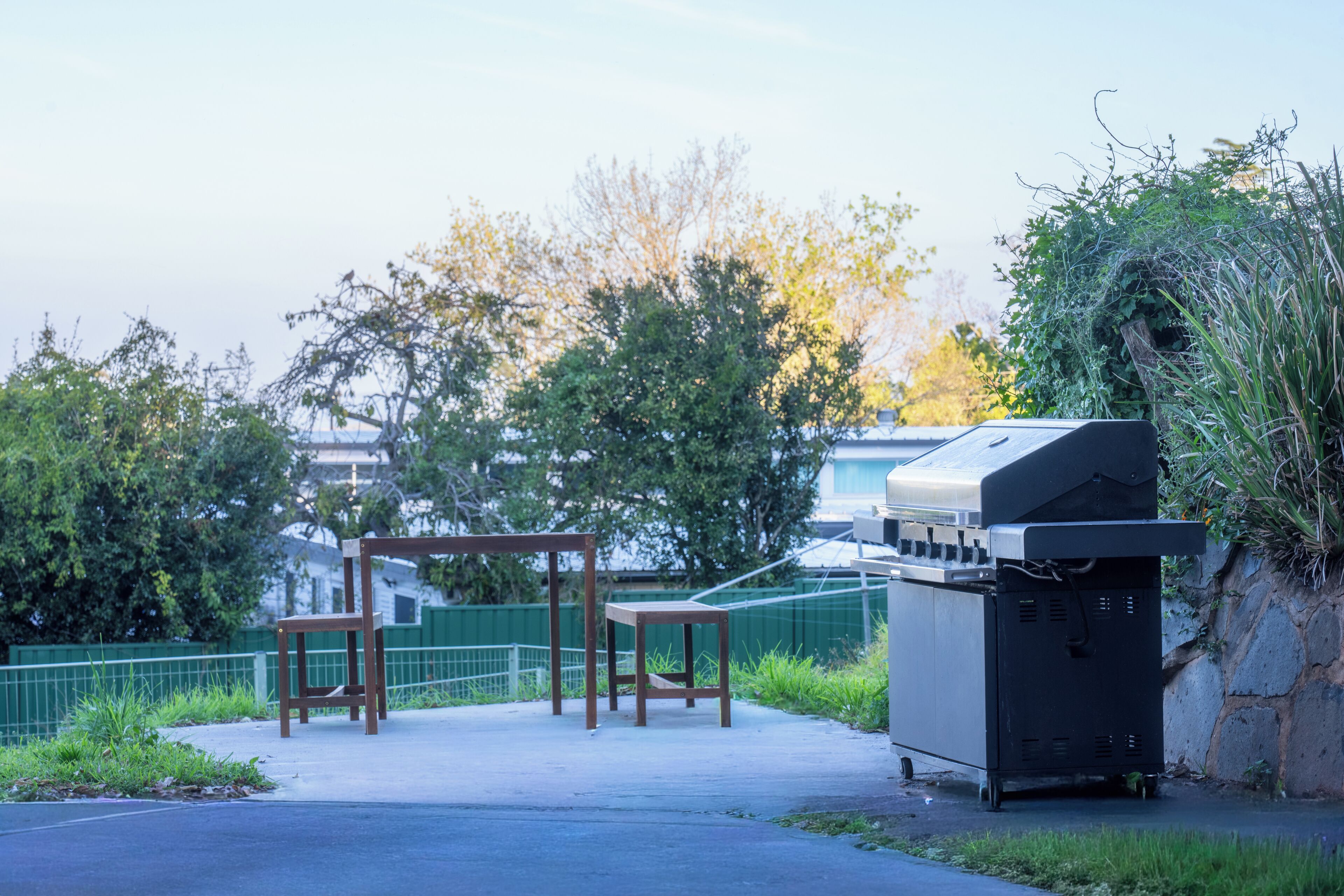 Eine Terrasse mit Gartenmöbeln, einem Grill und einer Steinmauer.